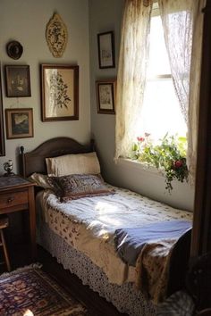 a bed sitting under a window next to a wooden table with a lamp on top of it