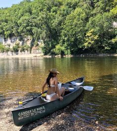 a woman is sitting in a canoe on the water