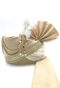 a hat with feathers and beads on it sitting on top of a white cloth bag