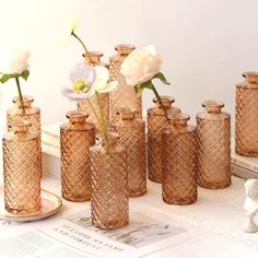 there are many vases with flowers in them on the table next to each other