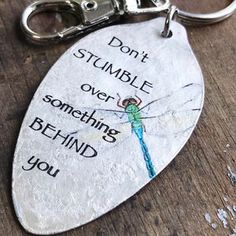 a metal keychain with a quote on it that says, don't stumble over something behind you