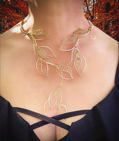 a woman wearing a gold necklace with leaves attached to it's neck and back