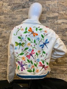 a woman's white jacket with dragon embroidered on the front and back, sitting in front of a brick wall