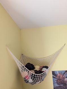 a hammock hanging from the ceiling in a room with yellow walls and pictures on the wall