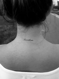 the back of a woman's neck with an inscription tattoo on her left side