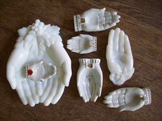 five white porcelain figurines with hands and feet sitting on a table next to each other