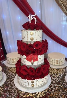 a wedding cake decorated with red roses and the number fifteen on it's top