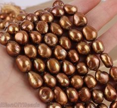 a woman's hand holding several brown pearls