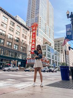 a woman standing on the sidewalk in front of a chicago sign