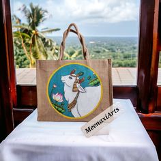 Immerse yourself in the world of artistry and craftsmanship with our Hand Painted Pichwai Cow Jute Tote. This one-of-a-kind art bag is a perfect blend of practicality and artistry, making it a unique gift for any art lover. Each tote is painstakingly hand-painted, showcasing the traditional Indian Pichwai art style that is renowned for its intricate details and vibrant colors. The tote's centerpiece is a beautifully detailed depiction of a sacred cow, a symbol of prosperity and love in Indian culture. Crafted from durable jute, this tote is not only a piece of art but also a sturdy companion for everyday use. The bag measures approximately Size- 34.5cm×41.5cm× 12cm  (Height×Width×Gusset) with zipper, providing ample space for your daily essentials. The bag's robust handles ensure comfortab Pichwai Cow, Sacred Cow, Pichwai Art, Traditional Marriage, Jute Totes, Wood Painting Art, Art Bag, Hand Painted Artwork, Welcome Gifts