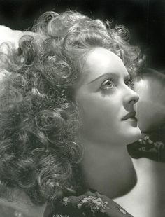 an old black and white photo of a woman with curly hair looking off to the side