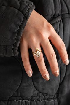 a woman's hand with a gold ring on top of her finger and black jacket