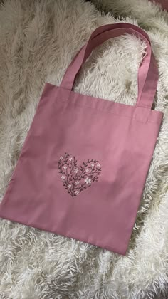 a pink tote bag sitting on top of a fluffy white blanket