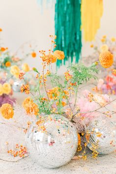 two disco ball vases filled with yellow flowers