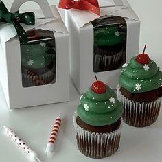 three cupcakes decorated with green frosting and topped with cherries are sitting next to each other