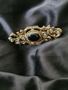 Celtic style with jet black stone (untested)  Vintage broach.  Beautiful gold tone.  Scottish vintage broach with the infinity and in an older victorian style. This has been adored by a lady of long ago and needs loved again as it has a story to tell and has more stories to see.  All my items are locally sourced here in Scotland and ready to go anywhere in the world Victorian Antique Gold Brooch For Formal Occasions, Antique Gold Victorian Brooch For Formal Occasions, Elegant Black Jewelry With Antique Finish, Victorian Brooches With Intricate Design For Formal Events, Victorian Brooches With Intricate Design For Formal Occasions, Victorian Brooch With Intricate Design For Formal Events, Victorian Brooches With Intricate Design For Formal Wear, Black Metal Brooch Jewelry, Antique Oval Brooches For Evening