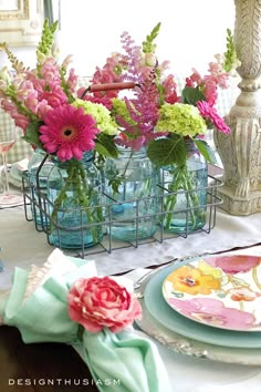 there are many flowers in the vases on the dining room table with plates and napkins