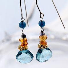 Blue and yellow dangling gemstone earrings with Tanzanite, blue Mystic Quartz, and yellow Citron semi-precious gemstones. These pretty earrings hang about 1.5 inches from the ear. The tear-drop shape Mystic Quartz anchors a series of colorful faceted stones wired to nickel-free silver French ear wire. They are light and comfortable simple and pretty. Blue Topaz Earrings With Gemstone Accents, Sapphire Briolette Gemstone Earrings, Blue Gemstone Crystal Drop Earrings, Blue Gemstone Accented Drop Earrings, Blue Drop Earrings With Gemstone Accents, Dangle Crystal Earrings With Gemstone Accents As Gift, Blue Gemstone Crystal Earrings, Blue Briolette Gemstones For Jewelry Making, Blue Drop Earrings With Ethical Gemstones