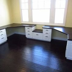 an empty room with white cabinets and black counter tops on the floor, in front of a window