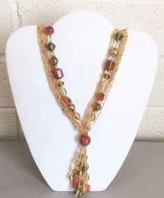 This is a vintage multi-strand glass bead tassel necklace. It has large bead strands and seed bead strands. The glass beads are in earth tone multi-colors; orange to rust, green, amber, some gold metal beads between the glass beads and some white beads.  It is 28" from end to end, the tassel portion adds another 4". It is in very good condition, without any noticeable wear.       See photos to evaluate condition. Brown Multi-strand Jewelry With Colorful Beads, Bohemian Multi-strand Long Necklace With Faceted Beads, Bohemian Long Multi-strand Necklace With Faceted Beads, Gold Beaded Multi-strand Lariat Necklace, Artisan Multi-strand Faceted Beads, Brown Multi-strand Jewelry With Dangling Beads, Orange Multi-strand Colorful Beads Jewelry, Bohemian Beaded Double Strand Lariat Necklace, Bohemian Double Strand Beaded Necklaces With Gold Beads