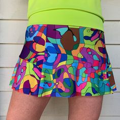 "This new style skort has a flat front panel with a ruffle that starts on the side and wraps around the back. Designed with a wide waistband that magically diminishes \"muffin top\" and a coordinating short beneath with a pocket on the side. It's the most flattering and comfortable skirt you will ever wear! Sizing:  XS/2, S/4-6, M/6-8, L/10-12, XL/14-16 Each item is handmade and there can be slight differences, however skirt lengths are generally: XS/13.5\", S/13.5\"-14\", M/13.5\"-14\", L/14.5\"-15\", XL/15\" Made with swimsuit fabric, it stretches in all the right places and always keeps it shape. Completely machine washable and dryable. This item may be returned for a full refund. Buyer must pay return shipping. This item is made to order and will take 1-2 weeks before shipping.  The vi Green Fitted Skirted Shorts, Fitted Tiered Skort With Built-in Shorts, Multicolor Skort For Spring, Multicolor Stretch Tiered Skirt, Multicolor Stretch Skirted Skort, Fitted Multicolor Skirted Bottoms, Fitted Green Tennis Skirt With Elastic Waistband, Green Mini Tennis Skirt With Elastic Waistband, Green Ruffled Skirted Skort