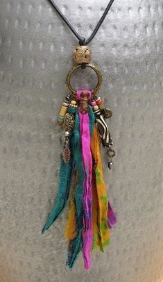 a multicolored necklace is hanging from a metal object on a silver surface with beads and chains