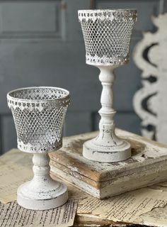 two white candlesticks sitting on top of an old book