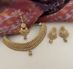 A beautiful 22K goldplated choker set with chandbalis and tika in a regal design to make heads turn! Unfold the euphoria of majestically embossed gold bridal jewelry set in an enticing style that will elevate your look. Details: Choker Necklace Width-1 Inch Choker Necklace Width with Centre Drop-1.75 Inches Earrings Length-2.5 Inches Earrings Width-1.25 Inches Weight of Each Earring-11.5 gms Tika Length-4.75 Inches All products are manufactured using traditional skills from our rich heritage of Pakistan Gold Jewelry, Bridal Necklace Set Gold, Heavy Gold Sets Jewelry Indian Design, Bridal Gold Jewellery Indian, Choker Necklace Indian Gold, Gold Choker Necklace Indian Bridal, Bridal Gold Jewellery Set, Gold Sets Jewelry Indian Design, Gold Choker Designs