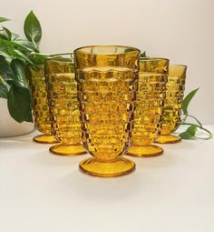 four yellow glass vases sitting next to each other