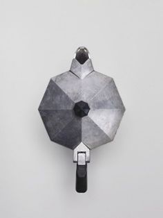 a metal object hanging from the side of a wall on a white surface with black handles