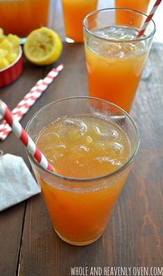 three glasses filled with orange juice on top of a wooden table