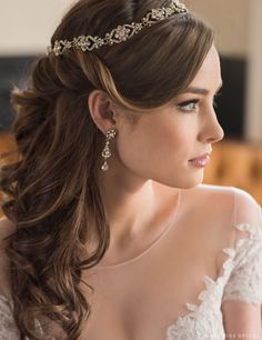 a woman with long hair wearing a bridal tiara and diamond earrings on her head