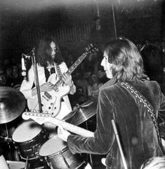 two men playing guitars in front of a crowd