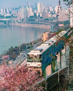 a train traveling down tracks next to a large body of water with tall buildings in the background