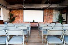 an empty room with rows of chairs and a projector screen on the wall behind it