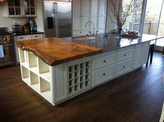 a large kitchen island in the middle of a wood floored area with stainless steel appliances