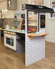 a miniature kitchen with white brick walls and wooden floors