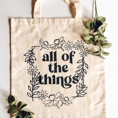 a tote bag with the words all of the things printed on it next to some plants