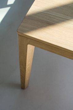 a wooden table sitting on top of a white floor next to a window with sunlight coming through it