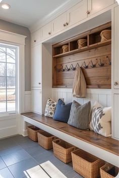 a wooden bench sitting under a window next to some baskets and pillows on top of it