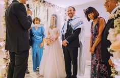 a man and woman standing next to each other in front of a wedding ceremony arch