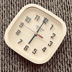 an analog clock sitting on top of a carpet