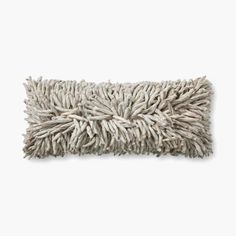 a white mop is laying on top of a gray pillow with frayed edges