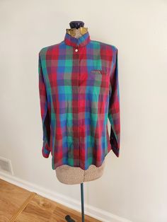 This vintage shirt is a darling addition to any wardrobe. Kelly Harper Petites 55% cotton / 45% polyester Made in Hong Kong The shirt features a plaid pattern in red, blue, and green. Tag size: 12 Shoulder to hem length: 21.5 inches Sleeve length: 22.25 inches Chest: 39 inches The shirt is in great vintage condition. Feel free to send me any questions! Casual Plaid Tops For Daywear, Multicolor Cotton Blouse With Buttons, Multicolor Button-up Top For Fall, Plaid Cotton Blouse With Buttons, Casual Multicolor Cotton Blouse, Multicolor Collared Top For Fall, Retro Relaxed Fit Multicolor Blouse, Retro Multicolor Relaxed Fit Blouse, Multicolor Button-up Top For Daywear