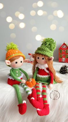 two crocheted dolls sitting on top of a white bed next to each other