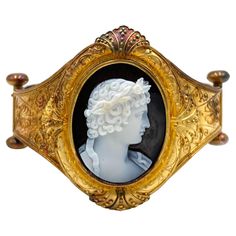 Antique lady's 18K yellow gold hard stone cameo hinged bangle bracelet. The oval cameo measures 33x26mm. The detailed carving depicts a Roman style portrait of a woman. The stone has a black background and white on the profile. The ornate bracelet is decorated with hand applied beading and twisted wire. * Circa 1880 * The clasp is hidden box style. * Great condition, slight chip on the corner of flower on the cameo. Jewelry Casket, Roman Style, David Webb, Roman Fashion, Vintage Bangles, Twisted Wire, Hinged Bangle, Estate Jewelry, Bangle Bracelet