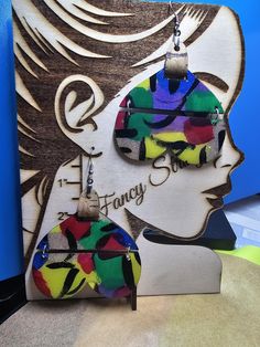 a pair of colorful earrings hanging from the side of a woman's head with words on it