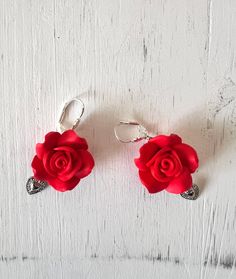 Handmade Red Rose Polymer Heart earrings.  Each delicate rose is carefully molded from high-quality polymer clay, showcasing intricate details and vibrant shades of red. The petals capture the essence of natural roses, providing a timeless and romantic touch. A heart charm dangles gracefully from each earring, adding a touch of mystique and individuality to your style. The contrasting colors create a unique and eye-catching combination. A Unique Gift: These earrings make an excellent gift for someone special or a unique addition to your own jewelry collection. They're suitable for various occasions, from casual outings to formal events. Each pair is lovingly handcrafted, ensuring no two are exactly alike. This uniqueness adds a personal touch to your accessories. 3.5cm in length Rose Flower Earrings For Wedding On Valentine's Day, Rose Flower Earrings For Valentine's Day Wedding, Rose Design Flower Earrings For Wedding On Valentine's Day, Valentine's Day Gift Rose Design Flower Earrings, Valentine's Day Rose Design Flower Earrings Gift, Rose Red Flower Earrings For Valentine's Day Wedding, Rose Red Flower Earrings For Wedding And Valentine's Day, Rose Red Earrings With Rose Design For Valentine's Day, Rose Red Flower Earrings For Valentine's Day Gift