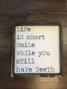 a wooden sign that says life is short smile while you still have teeth