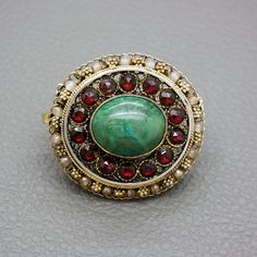 "A one of a kind gilt silver filigree brooch, set with blue / green Eilat stone and reg glass garnets. The brooch is a great quality traditional handwork of a Yemenite Israeli jeweler from 1950's - 1960's. Due to a hidden bale you may choose to wear this item as a brooch or as a pendant. You may choose to buy this item on its own or or with a matching 20 inches (50 cm) gold plated sterling silver rope chain, shown on the photos. The brooch will be shipped in a gift box. A lovely gift idea! The b Heirloom Oval Gemstone Brooches, Traditional Yellow Gold Pendant Brooches, Antique Yellow Gold Filigree Brooches, Formal Filigree Pendant Brooch, Heirloom Filigree Oval Brooch, Heirloom Style Oval Filigree Brooch, Heirloom Oval Filigree Brooch, Antique Brooch With Intricate Pendant Design, Antique Pendant Brooch With Intricate Design